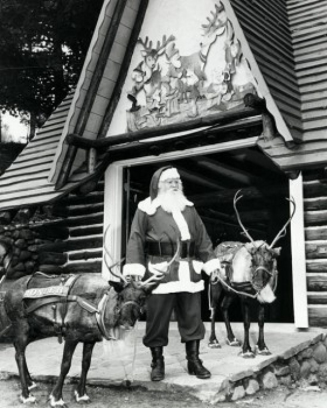 Santa Claus standing with two reindeer in front of a building Canvas Art - (18 x 24)