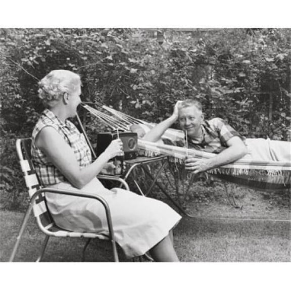 Senior Woman Sitting in a Chair & a Senior Man Lying in a Hammock Beside Her Poster Print - 18 x 24 in.