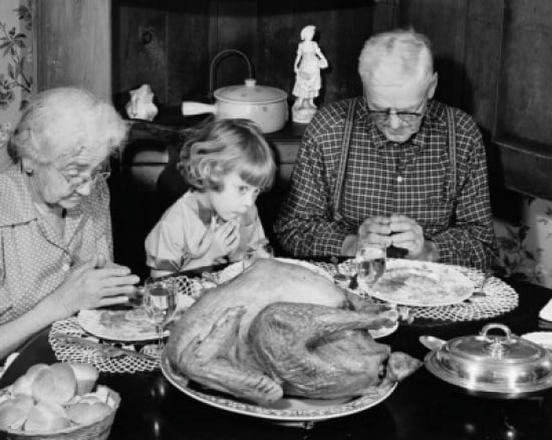 Senior couple praying with their granddaughter at a dining table on Thanksgiving Day Canvas Art - (18 x 24)