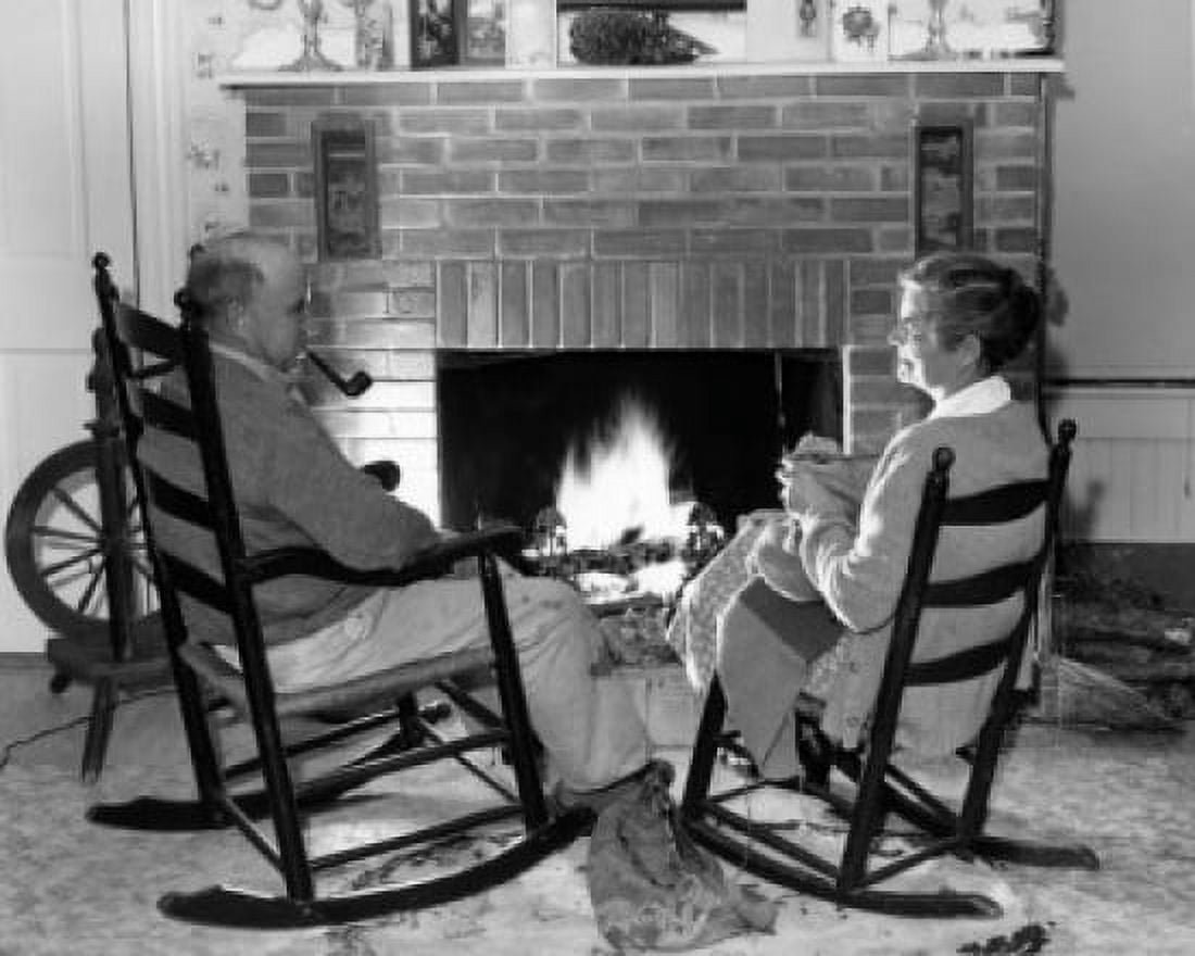 Senior couple sitting on rocking chairs in front of fireplace Canvas Art - (18 x 24)