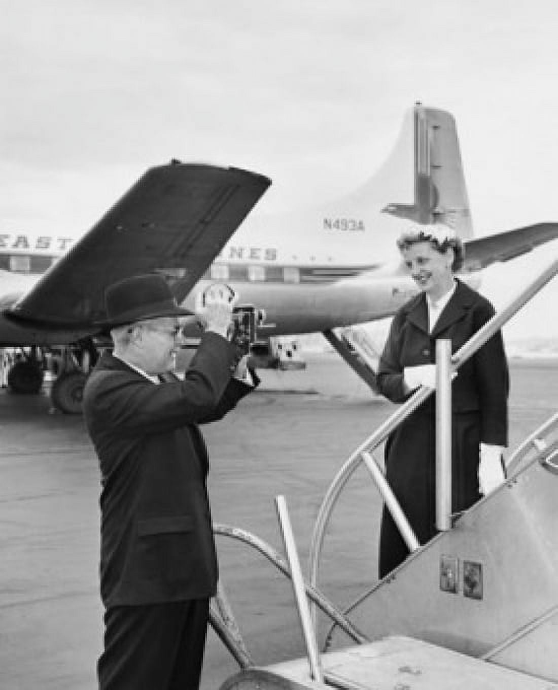 Senior man taking a picture of a senior woman at an airport Canvas Art - (24 x 36)