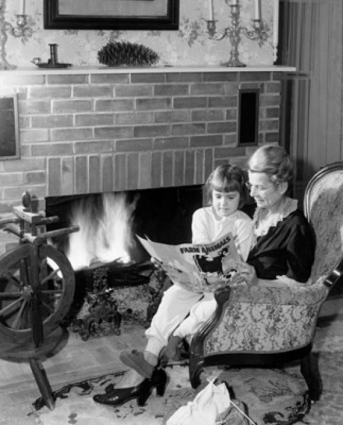 Senior woman reading story to her granddaughter near fireplace Canvas Art - (24 x 36)