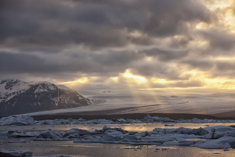 Shafts of sunlight shine on the ice calves floating in glacial lagoon jokulsarlon at the base of breioamerkurjokull iceland Canvas Art - Robert Postma Design Pics (38 x 24)