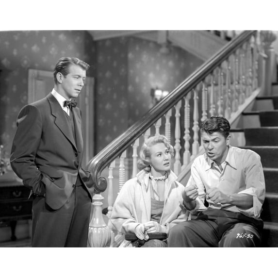 She's Working Her Way Through College Man in Black Suit and Bow Tie Stood In front of Two People Seated on Staircase Photo Print (24 x 30)