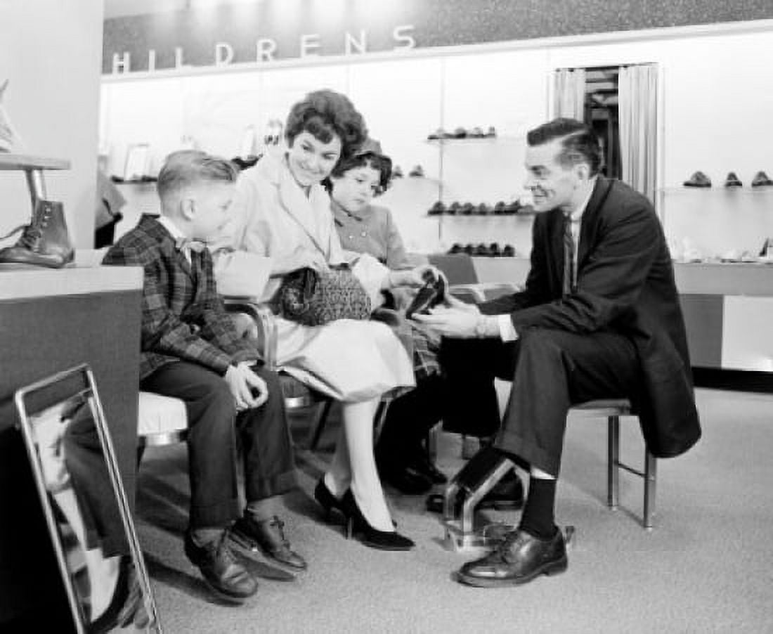Shop assistant showing boy shoe to mother with son and daughter Canvas Art - (18 x 24)