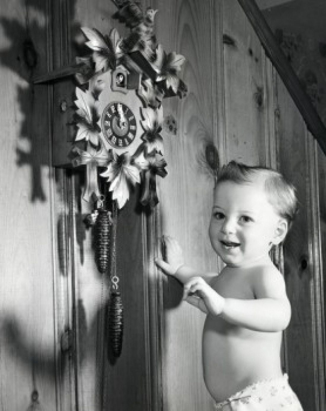 Side profile of a baby boy standing near a cuckoo clock and smiling Canvas Art - (24 x 36)