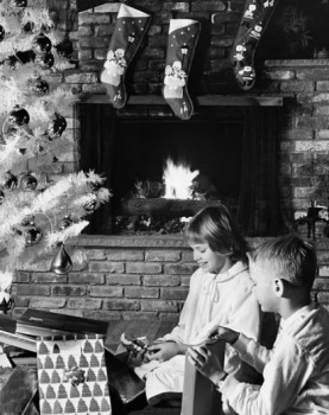 Side profile of a girl and her brother unwrapping Christmas presents near a fireplace Canvas Art - (24 x 36)