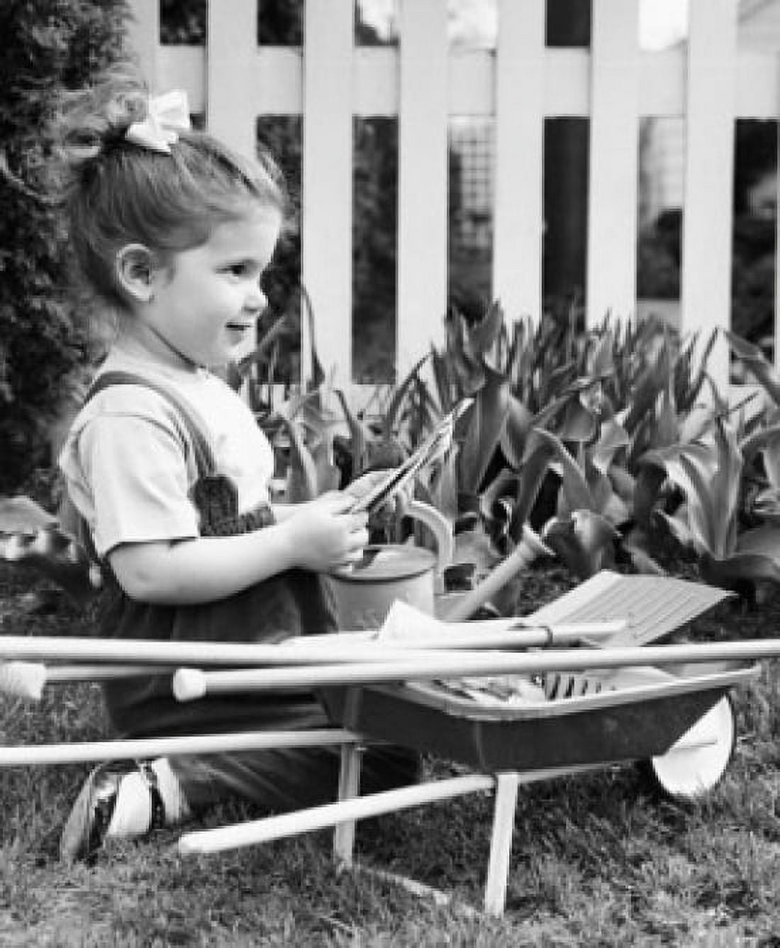 Side profile of a girl holding seed packets in a garden and smiling Canvas Art - (24 x 36)