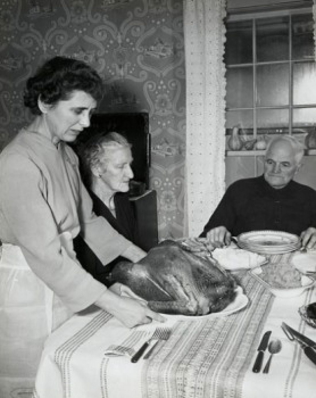 Side profile of a mature woman serving a roasted turkey to her parents on Thanksgiving Day Canvas Art - (24 x 36)