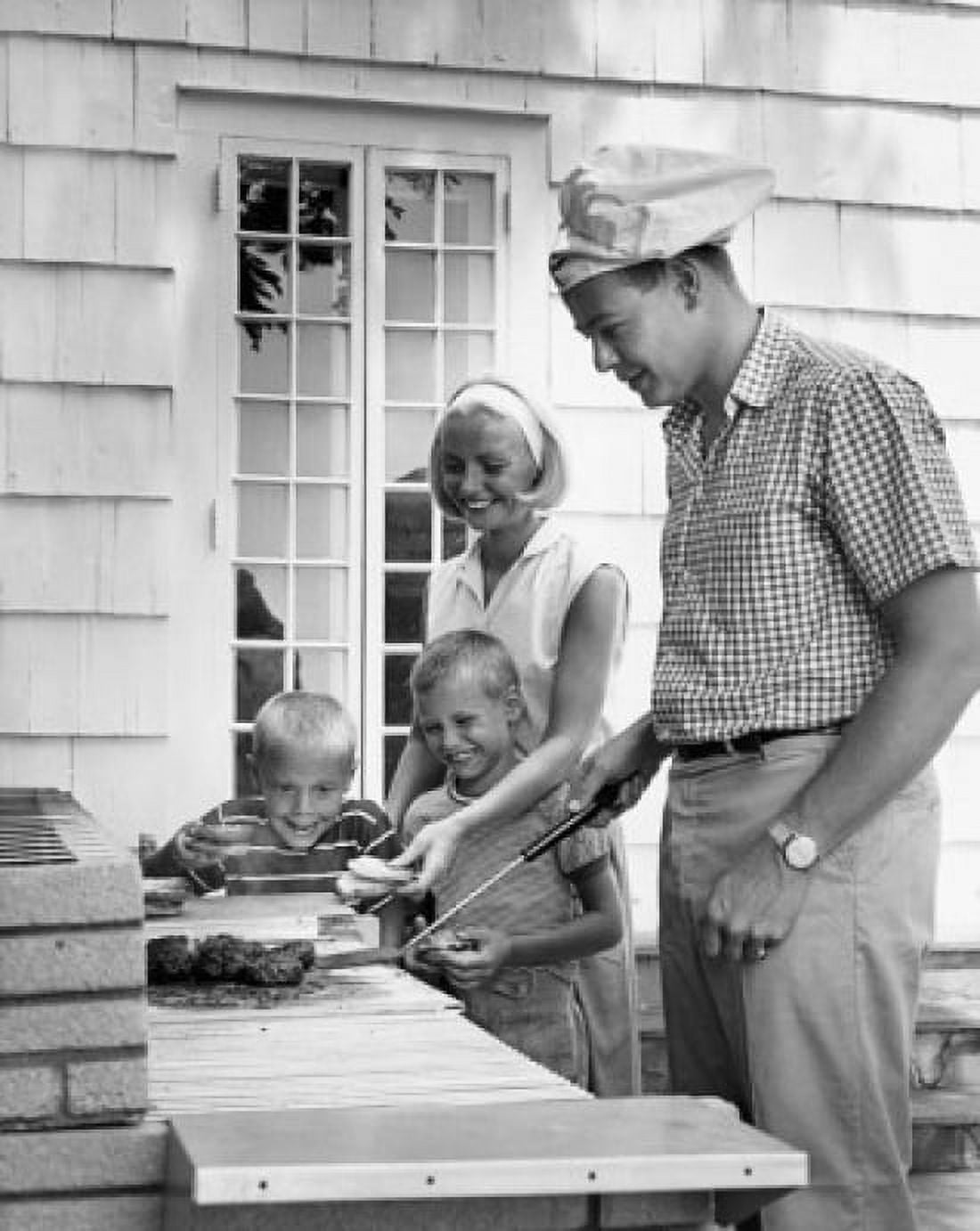 Side profile of a mid adult man cooking food with his wife and two children standing beside him Canvas Art - (18 x 24)