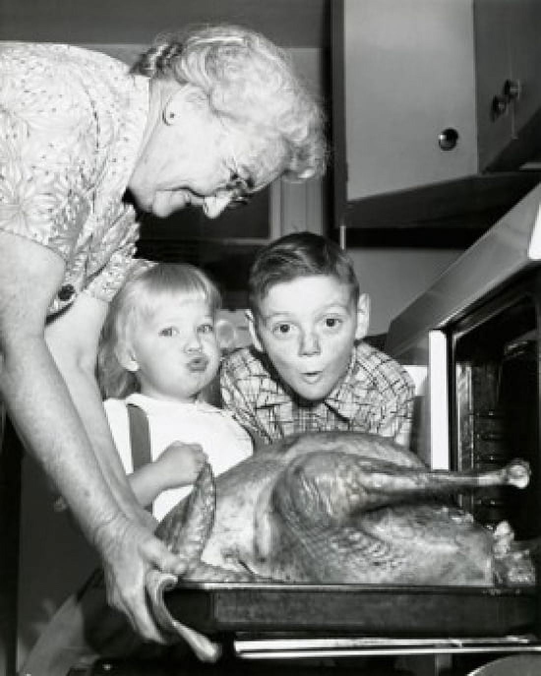 Side profile of a senior woman taking a roasted turkey out of an oven with her grandchildren looking surprised Canvas Art - (18 x 24)