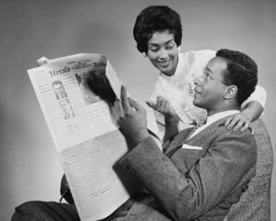 Side profile of a young man holding a newspaper with a young woman standing beside him Canvas Art - (18 x 24)