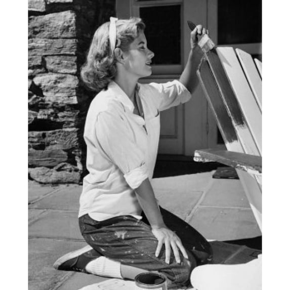 Side profile of a young woman painting an adirondack chair Poster Print (18 x 24)
