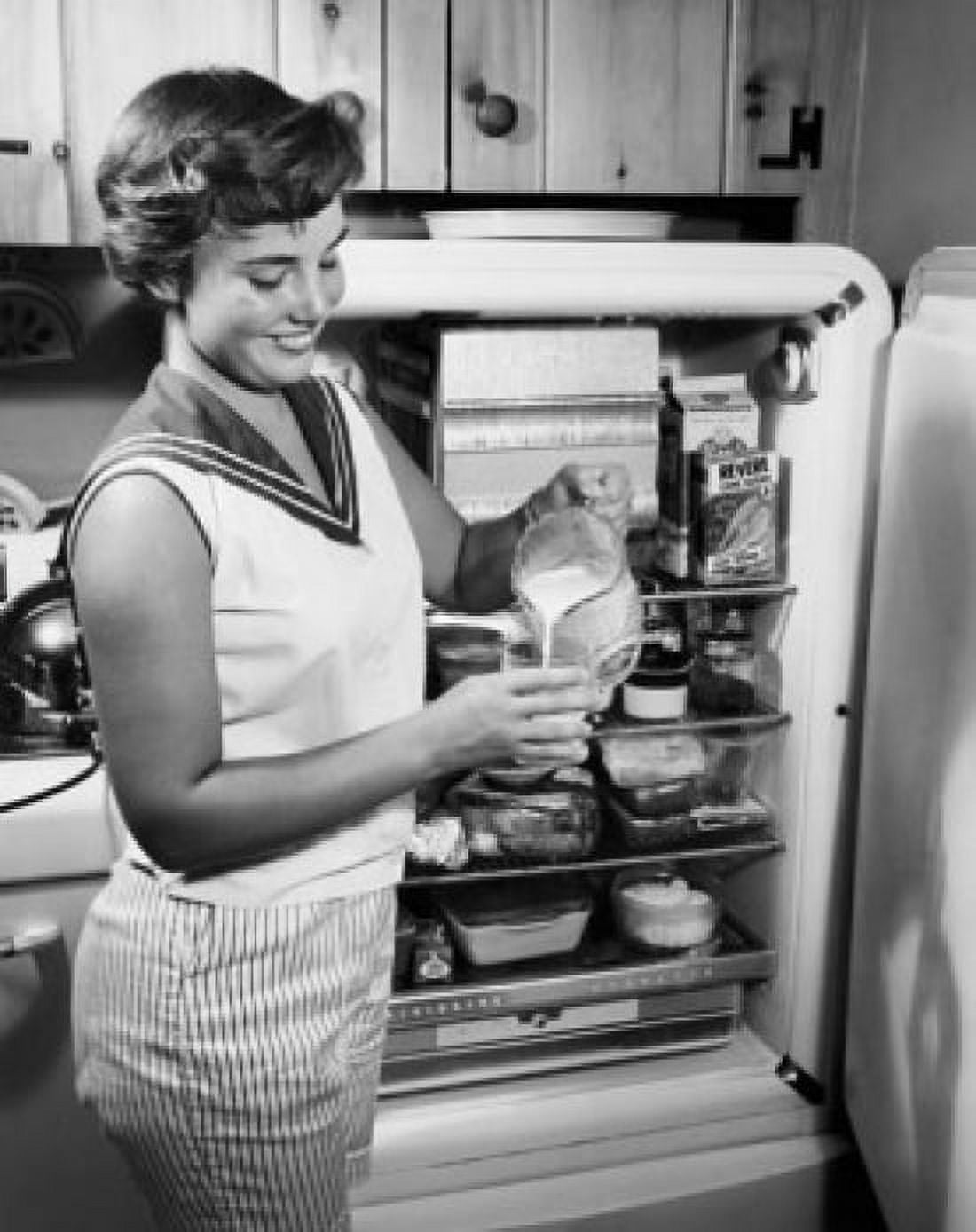 Side profile of a young woman standing near a refrigerator pouring milk Canvas Art - (18 x 24)