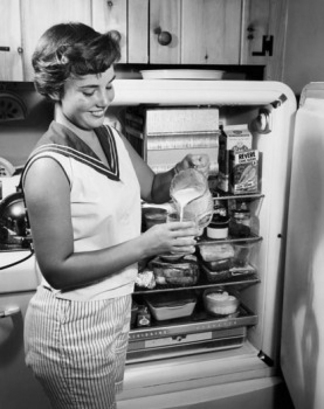 Side profile of a young woman standing near a refrigerator pouring milk Canvas Art - (24 x 36)