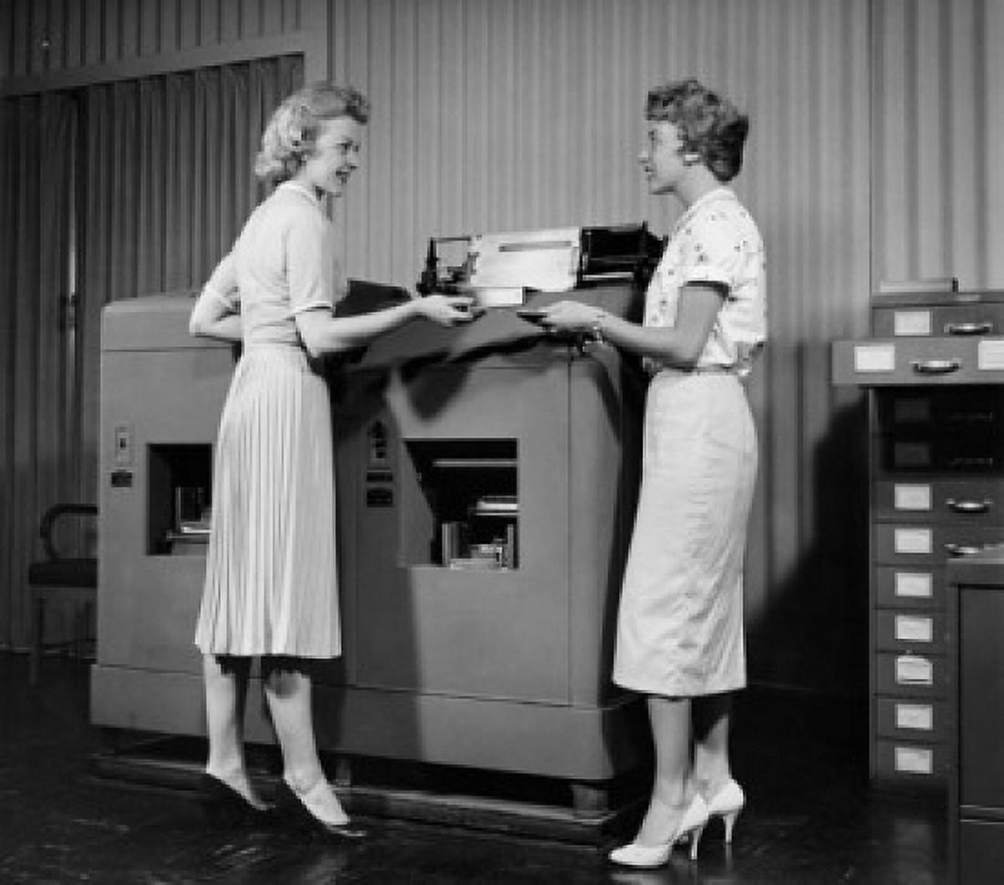 Side profile of two businesswomen standing in front of a machine Canvas Art - (18 x 24)