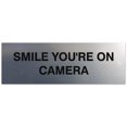 thumbnail image 1 of Signs ByLITA Basic Smile you're on camera Sign - Laser-Engraved Lettering | Durable ABS Plastic | Vibrant Colors | Powerful Foam Tape (Brushed Silver) - Large, 1 of 2