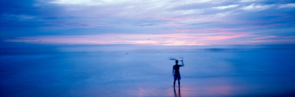 Silhouette of a man carrying a surfboard over his head on the beach Costa Rica Canvas Art - Panoramic Images (36 x 12)