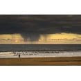 thumbnail image 1 of Silhouette of a person and dog walking on the beach at the water's edge under storm clouds with rain streaks and a sunse, 1 of 4