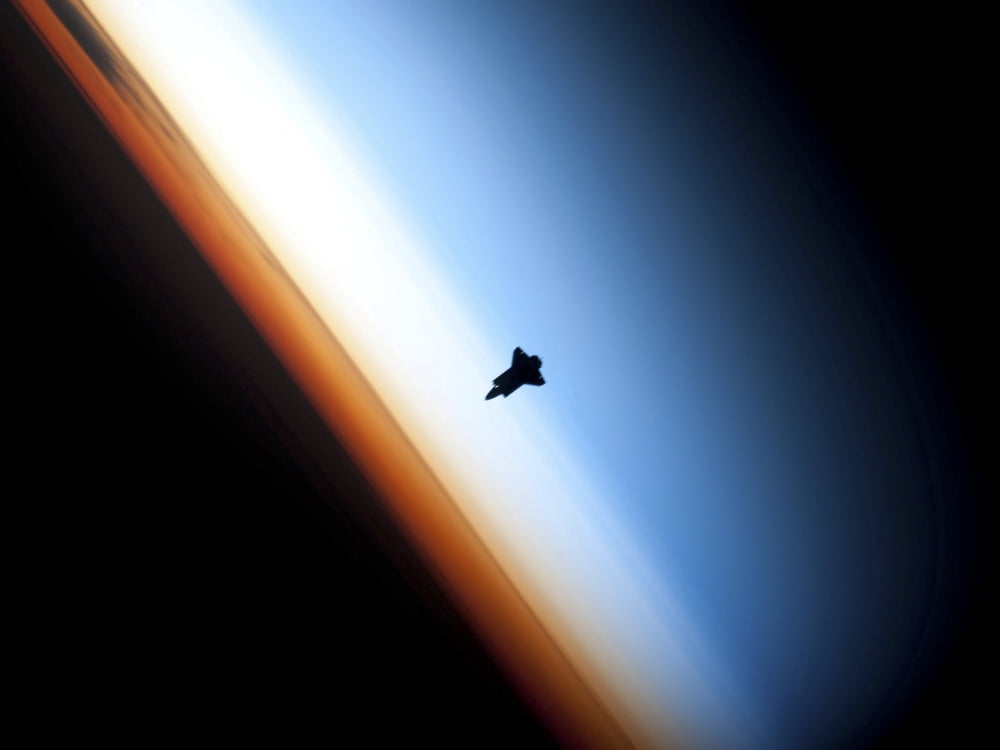 Silhouette of space shuttle Endeavour over Earths colorful horizon Canvas Art - Stocktrek Images (33 x 25)
