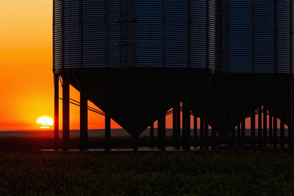 Silhouette of a row of large metal grain bins with the sunrise in the background and colourful clouds Alberta Canada Canvas Art - Michael Interisano Design Pics (19 x 12)