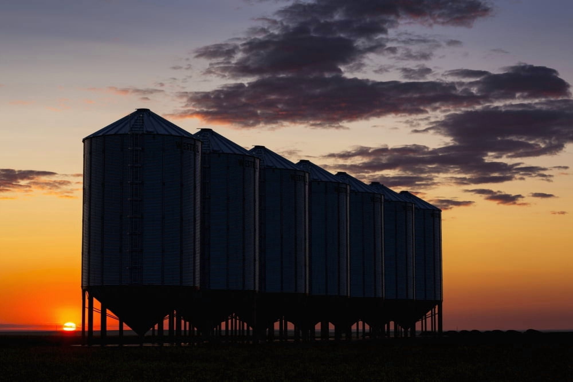 Silhouette of a row of large metal grain bins with the sunrise in the background and colourful clouds Alberta Canada Canvas Art - Michael Interisano Design Pics (38 x 24)
