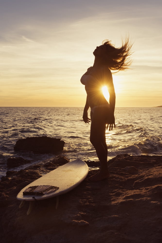 Silhouette of a woman standing on a rock at the waters edge with her surfboard at sunsetTarifa cadiz andalusia spain Canvas Art - Ben Welsh Design Pics (12 x 19)