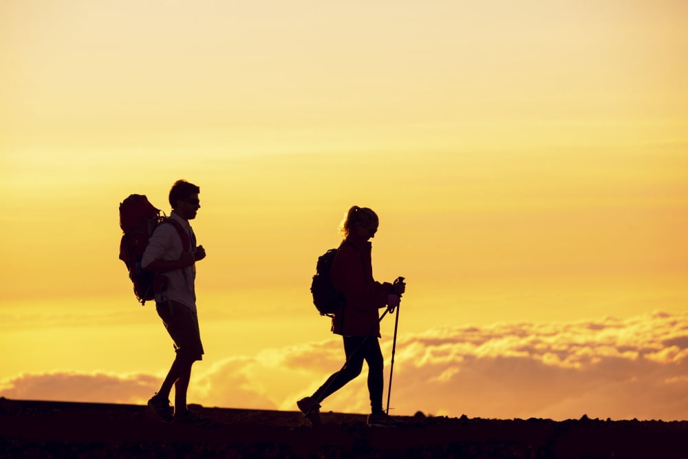 Silhouettes of two hikers with backpacks walking at sunset Trekking and enjoying the sunset view from mountain top above the clouds Canvas Art - Design Pics Vibe Design Pics (19 x 12)