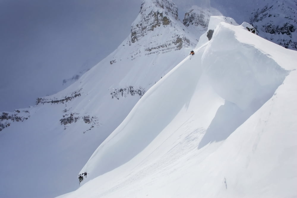 Skier On Crest Of Big Drop Dwarfed By Mountain Canada British Columbia Icefall Lodge Canvas Art - Ewan Nicholson Photography Design Pics (34 x 22)