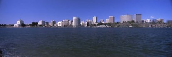Skyscrapers along a lake Lake Merritt Oakland California USA Canvas Art - Panoramic Images (36 x 12)