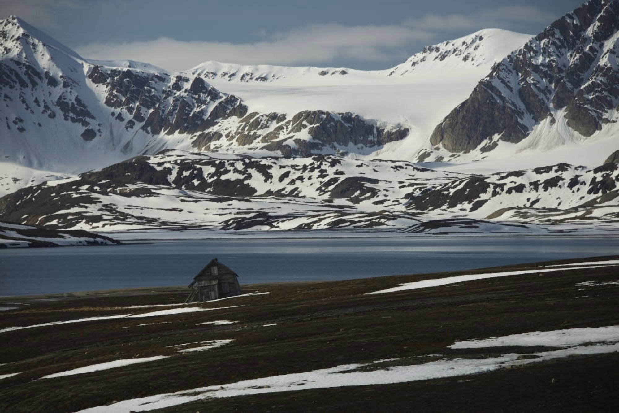 Small wooden cabin on the shore of the Arctic Ocean and snow covered mountains Spitsbergen Svalbard Norway Canvas Art - Nick Dale Design Pics (19 x 12)