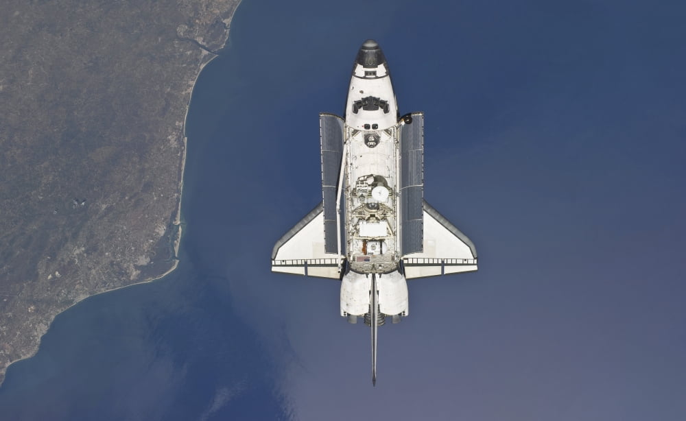 Space shuttle Atlantis backdropped by a colorful Earth as the shuttle approaches the International Space Station Canvas Art - Stocktrek Images (36 x 22)