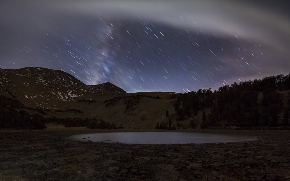 Star trails and the blurred band of the Milky Way above a lake in the Eastern Sierra Nevada Canvas Art - Dan BarrStocktrek Images (18 x 12)