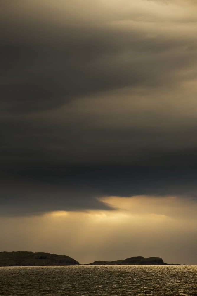 Storm clouds with some illumination from sunlight glowing over silhouetted mountains and water Scotland Canvas Art - John Short Design Pics (12 x 19)