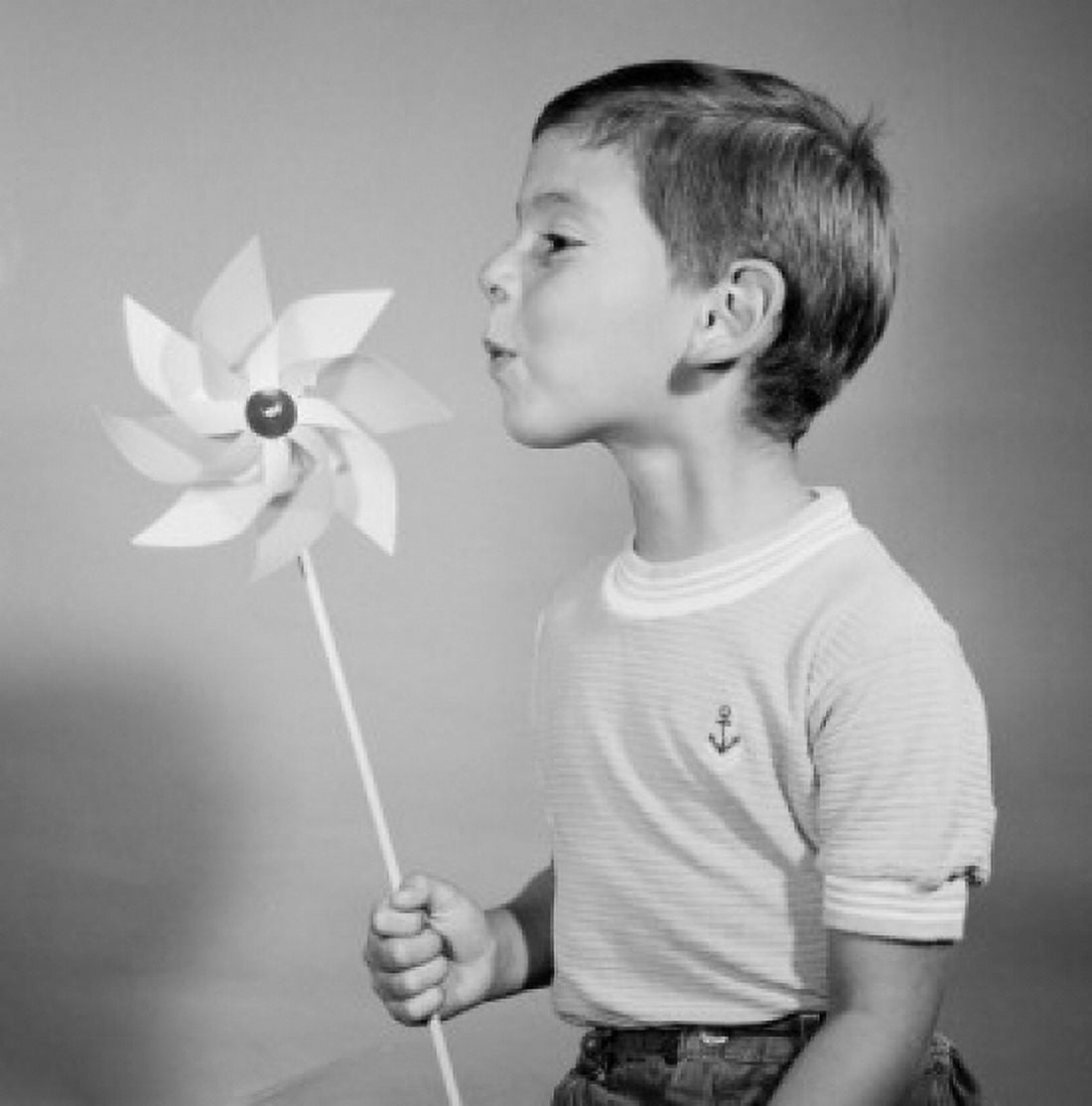 Studio shot of boy blowing at pinwheel Canvas Art - (24 x 36)