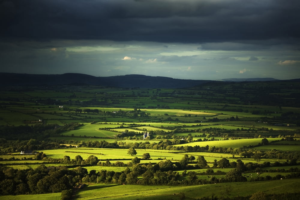 Sunlight illuminates lush green farmland as it shines through storm clouds Canvas Art - George Munday Design Pics (19 x 12)
