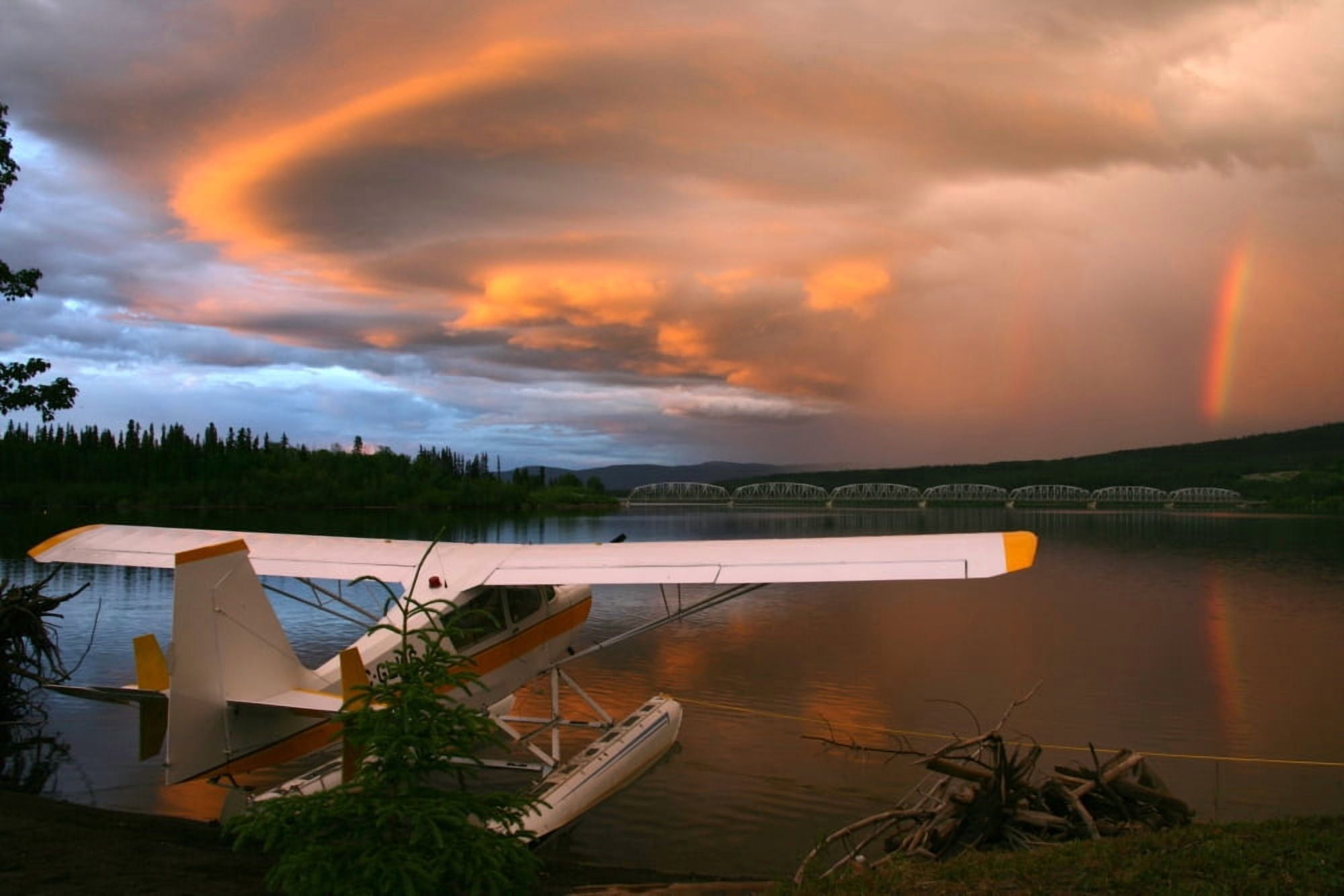 Sunlit Storm Clouds Over A Float Plane With Rainbow And Teslin Bridge In Background Teslin Lake Yukon Canvas Art - Robert Postma Design Pics (34 x 22)