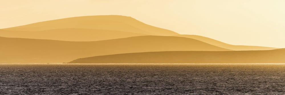 Sunrise over orange hills and blue ocean Antarctica Canvas Art - Nick Dale Design Pics (26 x 8)
