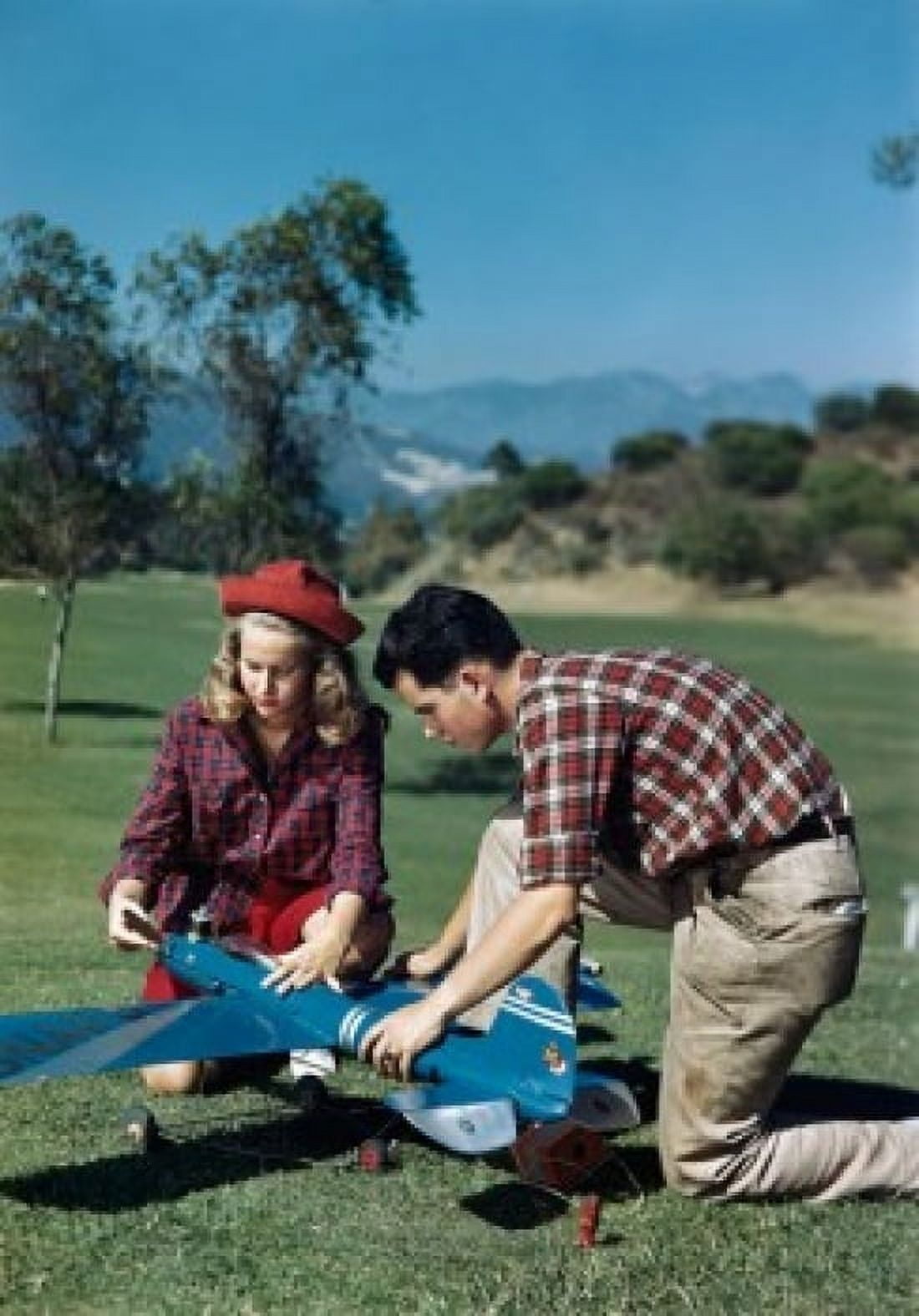 Teenage boy and a teenage girl repairing a model airplane in a park Canvas Art - (24 x 36)