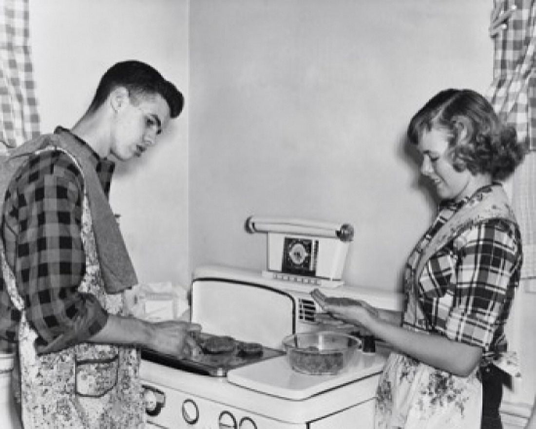 Teenage couple cooking hamburgers on a stove Canvas Art - (24 x 36)