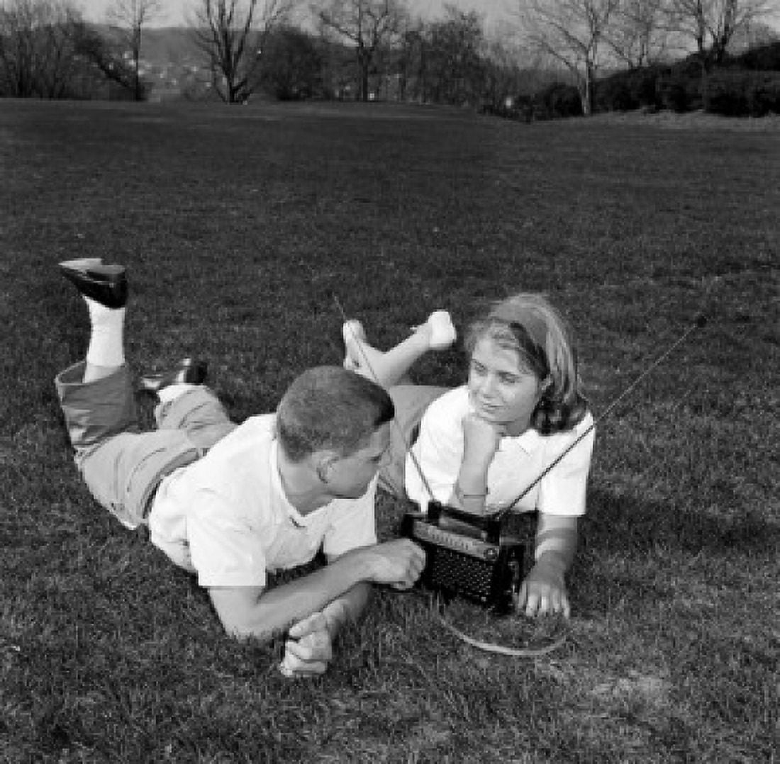 Teenage couple lying on lawn listening to radio Canvas Art - (18 x 24)
