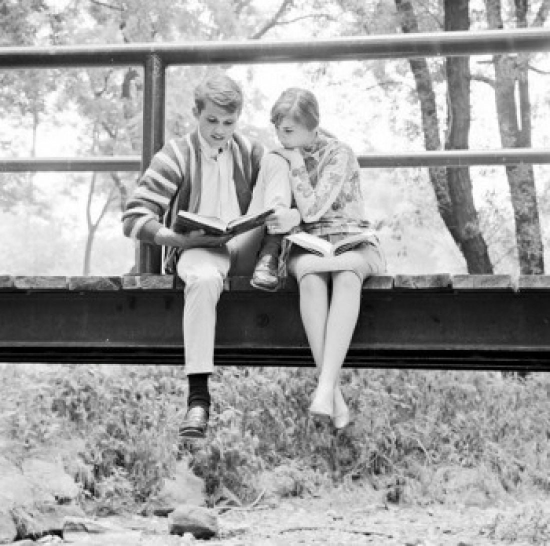 Teenage couple sitting on footbridge doing homework Canvas Art - (18 x 24)