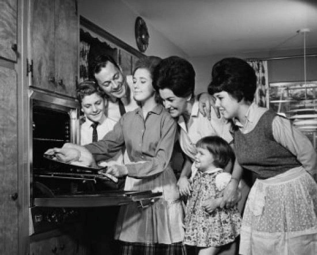 Teenage girl putting a turkey into an oven with her family standing beside her Canvas Art - (18 x 24)