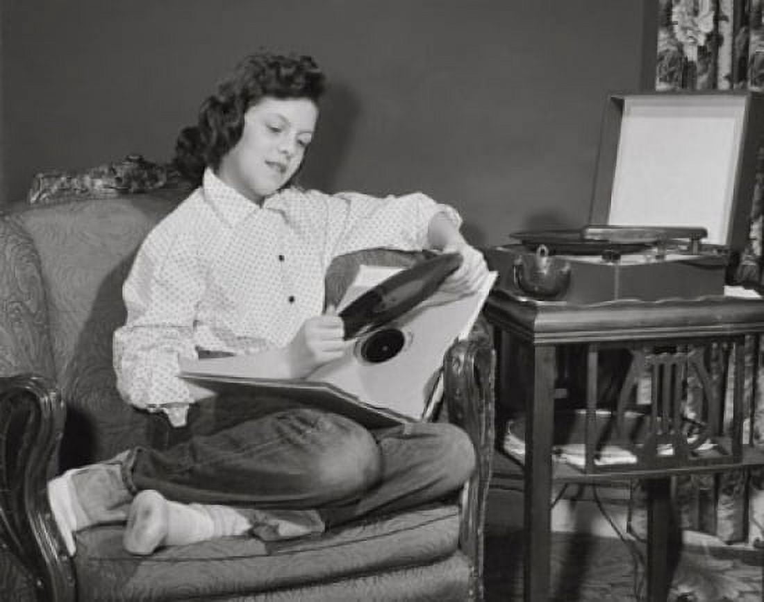Teenage girl sitting in armchair and holding record Canvas Art - (24 x 36)