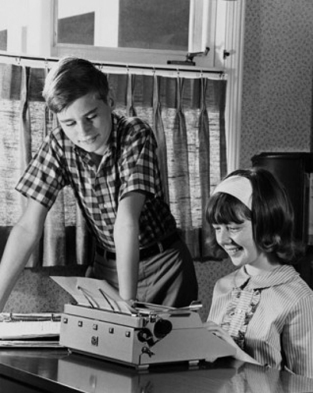 Teenage girl typing on a typewriter and her brother standing beside her Canvas Art - (24 x 36)