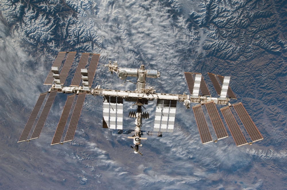 The International Space Station backdropped by a rugged Earth terrain Canvas Art - Stocktrek Images (35 x 23)