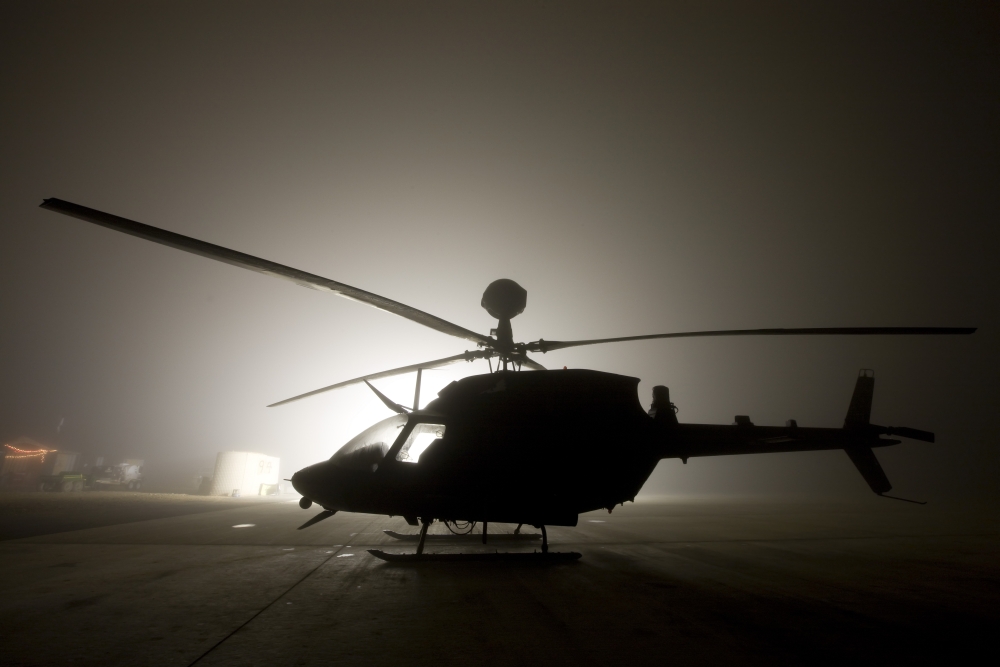 The illumination from the bright light silhouettes a OH-58D Kiowa helicopter during thick fog Canvas Art - Terry MooreStocktrek Images (35 x 23)