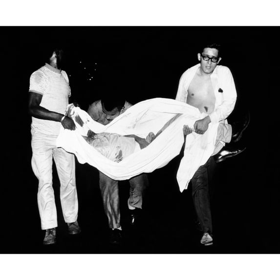 Three Men Carry Body Of A Youth Who Died After Apparently Falling From A Rooftop During Third Night Of Civil Disorder In