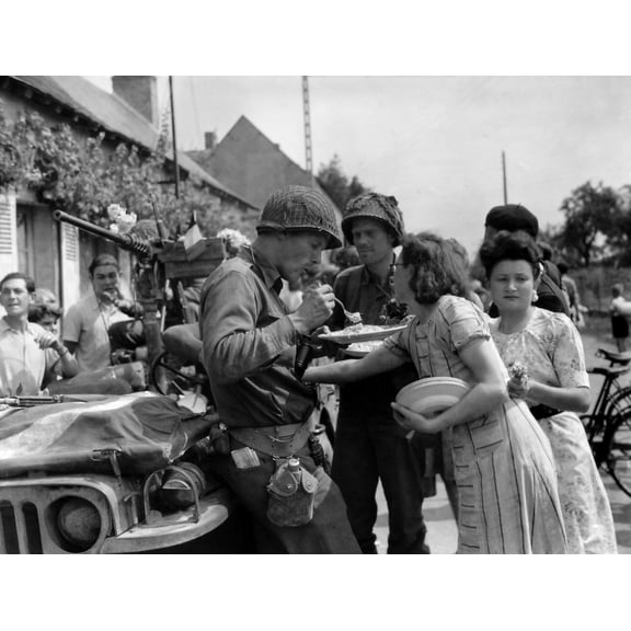 Three U.S. Soldiers Eat On Homemade Food On Plates Prepared By A French Woman In Summer 1944. The Liberated Civilians Also Decorated Their Jeep With Flowers. Location Is Somewhere In Normandy History