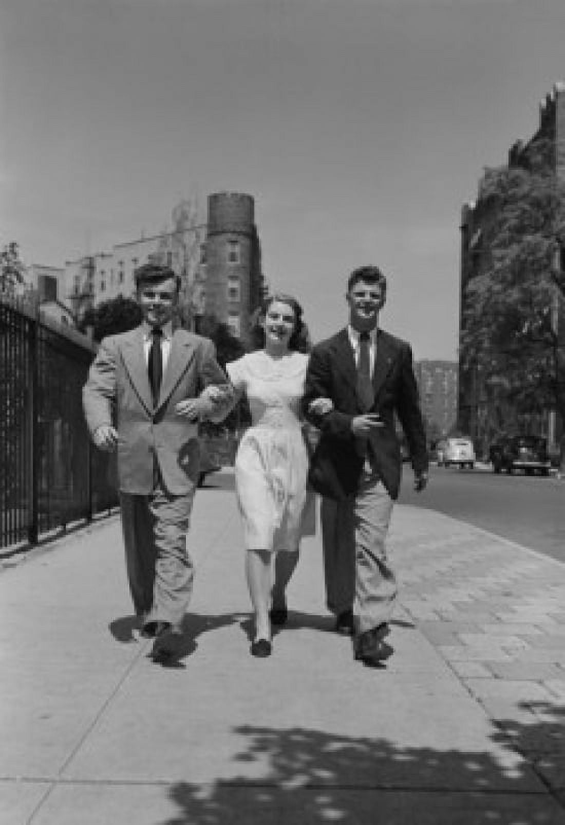 Three friends walking arm in arm in street Canvas Art - (24 x 36)